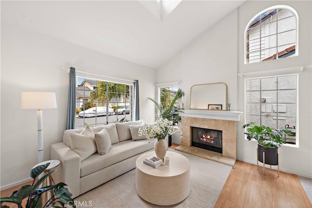 living area with high vaulted ceiling, baseboards, a fireplace, and wood finished floors