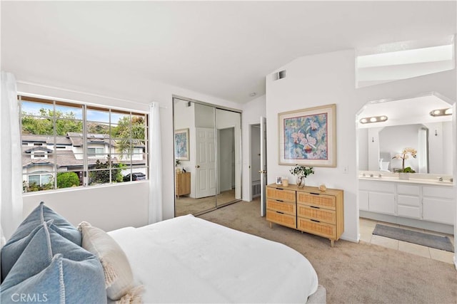 bedroom with light colored carpet, a sink, ensuite bath, visible vents, and a closet