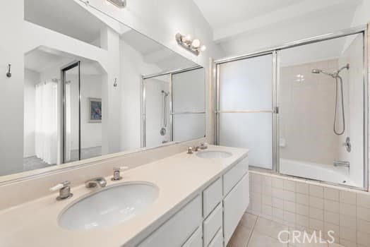 bathroom featuring tiled shower / bath combo, double vanity, a sink, and tile patterned flooring