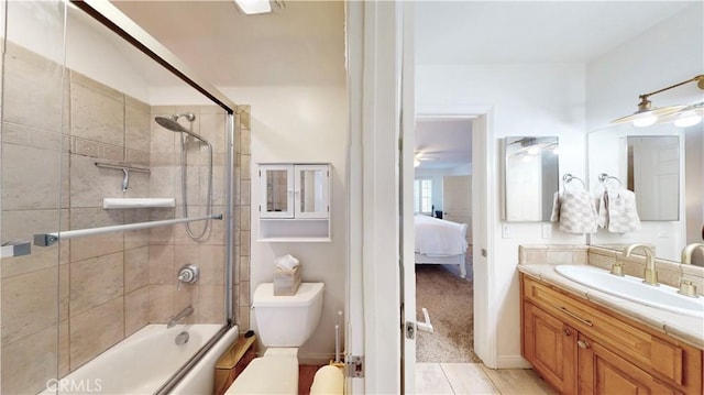 ensuite bathroom featuring tile patterned flooring, combined bath / shower with glass door, toilet, vanity, and ensuite bathroom