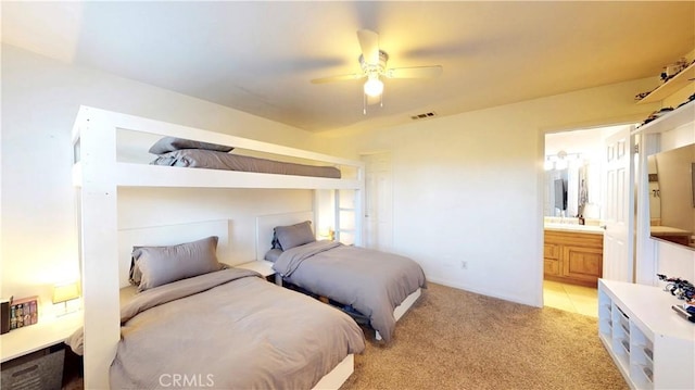 bedroom featuring a sink, ensuite bathroom, visible vents, light colored carpet, and ceiling fan