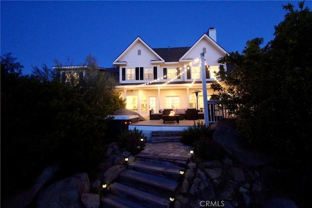 back of house at night with a chimney and an outdoor fire pit