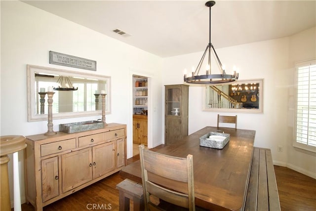 dining area featuring an inviting chandelier, dark wood-style flooring, visible vents, and baseboards
