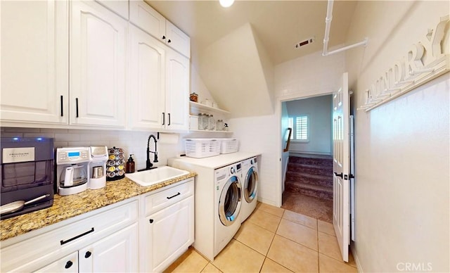 washroom with washing machine and dryer, light tile patterned flooring, a sink, and cabinet space