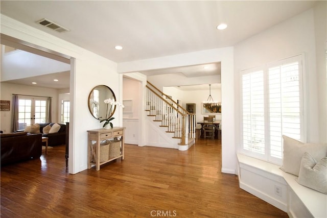 interior space featuring stairway, an inviting chandelier, wood finished floors, and visible vents