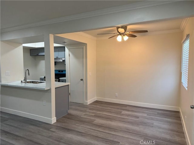 1709 Normandy Pl Unit B, Santa Ana, CA 92705 - kitchen featuring dark wood finished floors, ceiling fan, under cabinet range hood, crown molding, and a peninsula