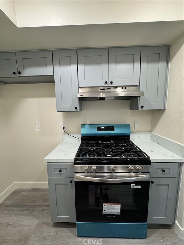 1709 Normandy Pl Unit B, Santa Ana, CA 92705 - kitchen featuring stainless steel gas range oven, under cabinet range hood, gray cabinets, light wood-style flooring, and light stone countertops