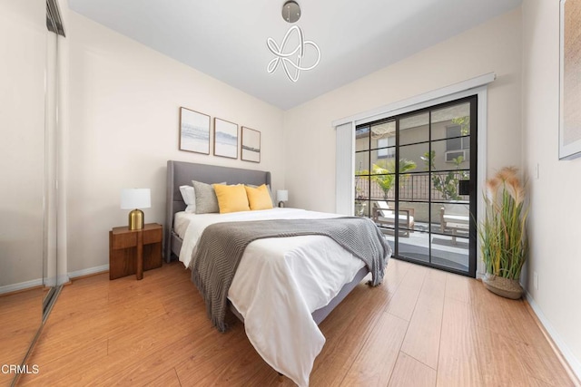 bedroom featuring baseboards, wood finished floors, and access to outside