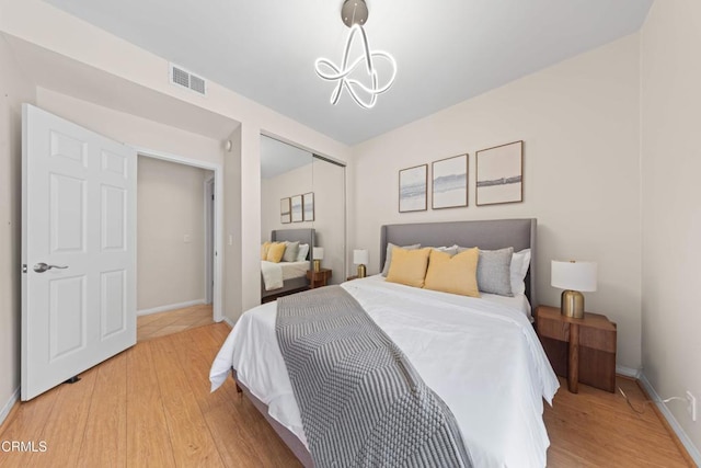 bedroom with baseboards, light wood-style floors, visible vents, and a closet