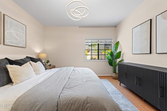 bedroom with light wood finished floors, baseboards, and a chandelier