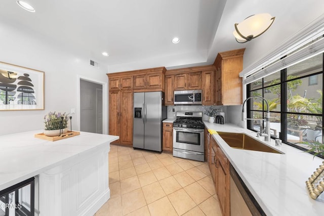 kitchen with brown cabinets, visible vents, appliances with stainless steel finishes, and a sink