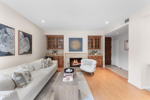 living area featuring recessed lighting, visible vents, light wood finished floors, and a premium fireplace