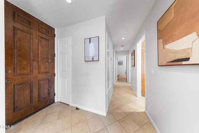 hallway featuring light tile patterned floors, baseboards, and recessed lighting