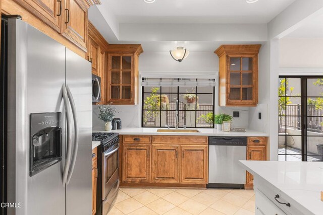 kitchen with light countertops, brown cabinets, stainless steel appliances, and a sink