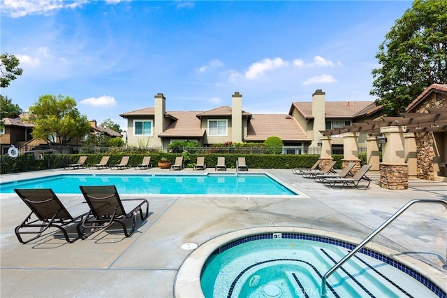 community pool featuring a residential view, a patio area, a hot tub, and fence