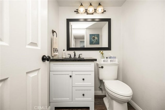half bathroom featuring baseboards, vanity, and toilet