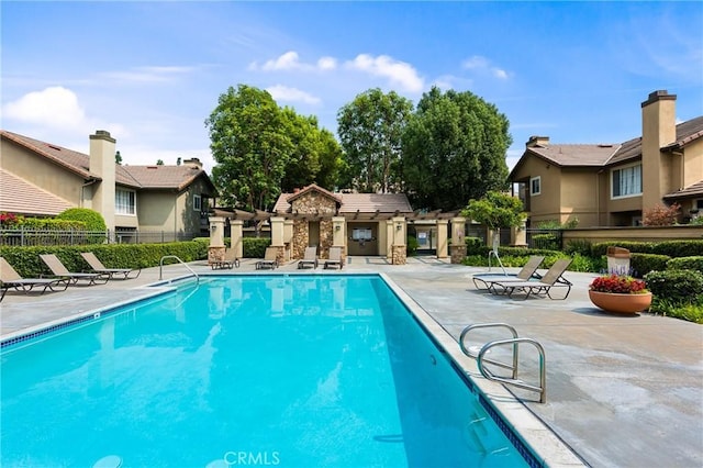 pool with fence, a patio area, and a residential view
