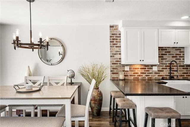 dining area featuring a chandelier, baseboards, and dark wood-style floors