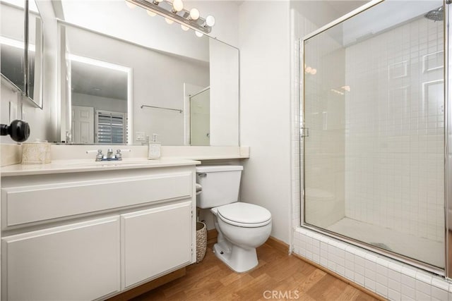 full bath featuring a shower stall, toilet, vanity, and wood finished floors
