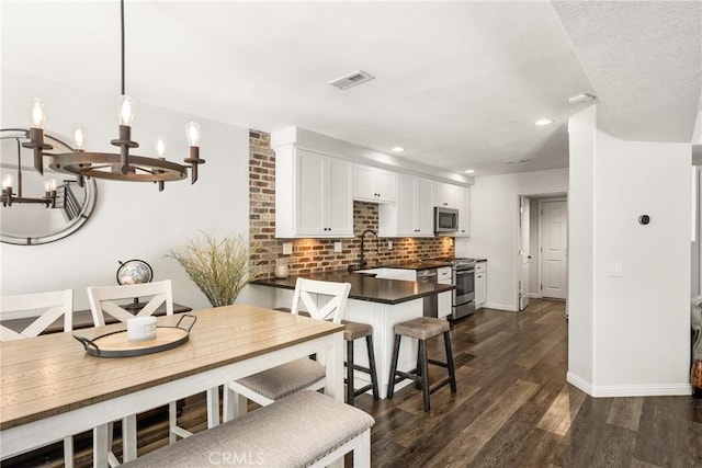 dining area with a chandelier, baseboards, visible vents, and dark wood-style floors