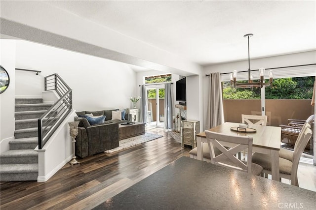 dining room featuring wood finished floors, baseboards, stairway, and an inviting chandelier