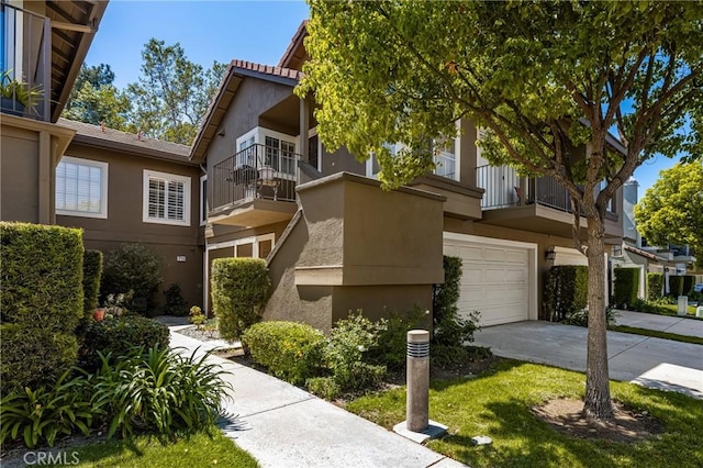view of property featuring a balcony, concrete driveway, and stucco siding