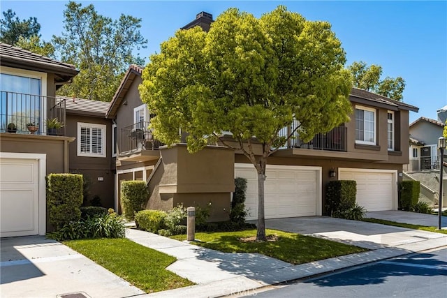 view of property with a garage, driveway, and stucco siding