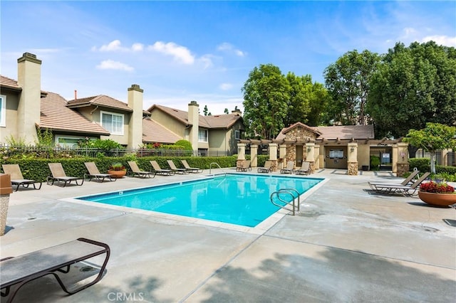 community pool with a patio area and fence