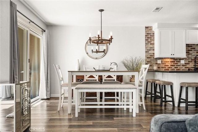 dining space with dark wood-type flooring, visible vents, and a notable chandelier