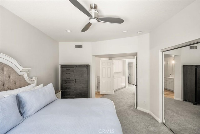 bedroom with ensuite bath, ceiling fan, light carpet, and visible vents