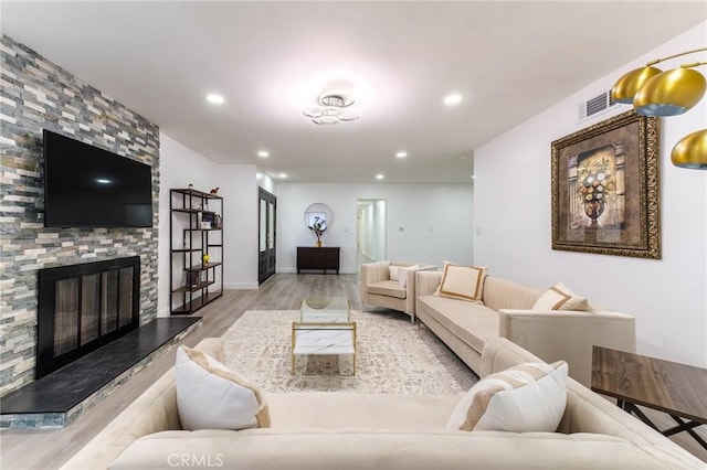 living room with recessed lighting, wood finished floors, visible vents, and a fireplace