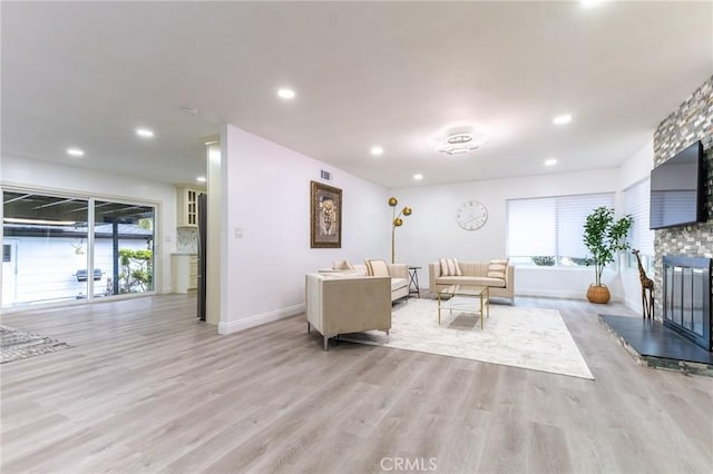 living area with a large fireplace, light wood-style flooring, baseboards, and recessed lighting