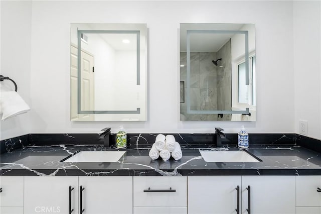 bathroom featuring a sink, double vanity, and tiled shower