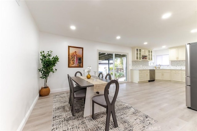 dining room with recessed lighting, light wood-type flooring, a healthy amount of sunlight, and baseboards