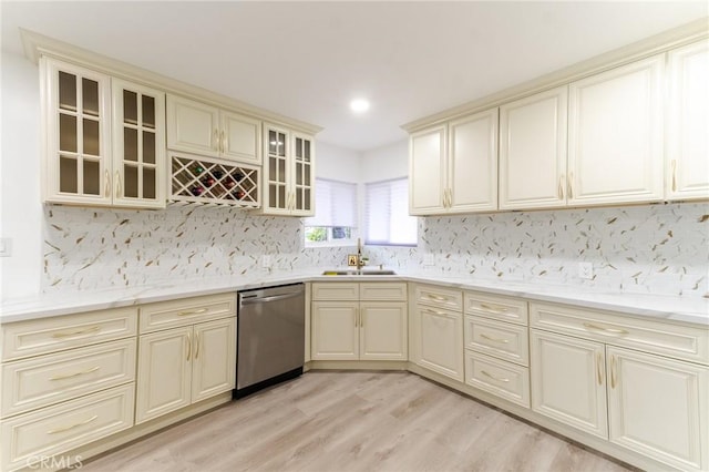 kitchen featuring cream cabinetry, stainless steel dishwasher, a sink, and light wood finished floors