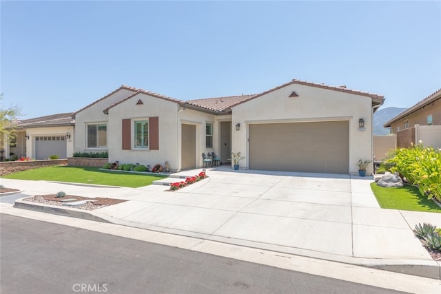 mediterranean / spanish-style house featuring a garage, a front lawn, stucco siding, concrete driveway, and a tile roof