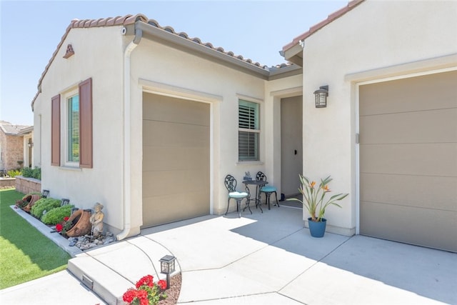 exterior space with a garage, stucco siding, a patio area, concrete driveway, and a tile roof