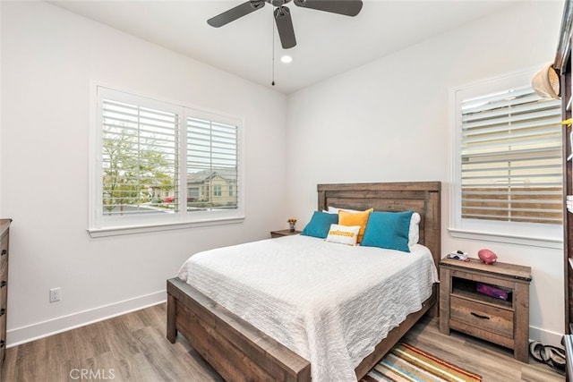 bedroom featuring baseboards, ceiling fan, multiple windows, and wood finished floors