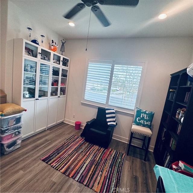 living area with baseboards, ceiling fan, and wood finished floors