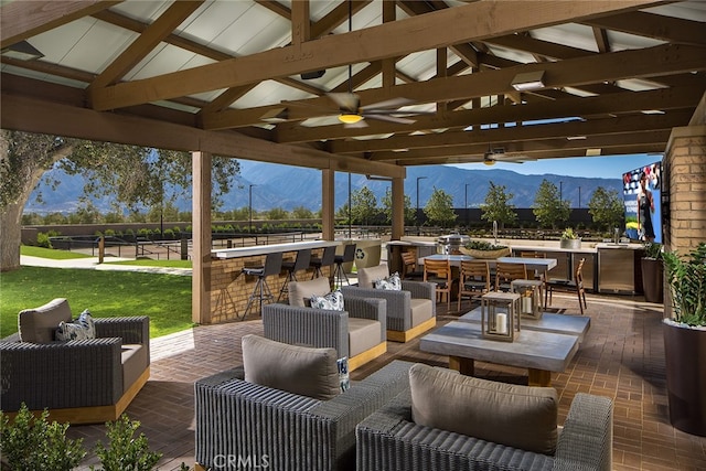 view of patio featuring ceiling fan, outdoor lounge area, a gazebo, a mountain view, and a bar