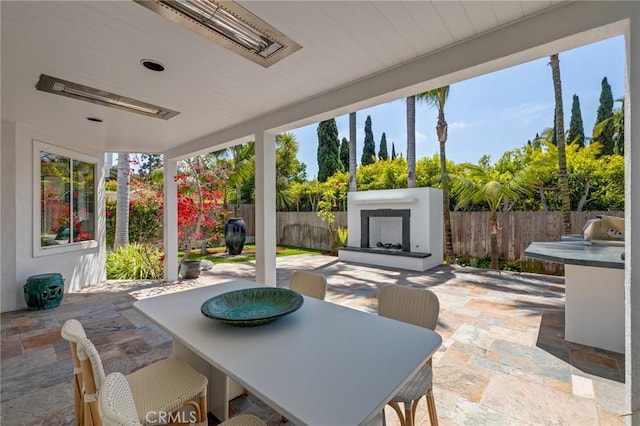 view of patio / terrace with outdoor dining space, a fenced backyard, and an outdoor fireplace