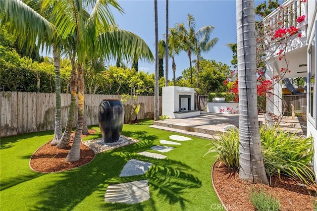 view of yard featuring a patio, an outdoor fireplace, and a fenced backyard