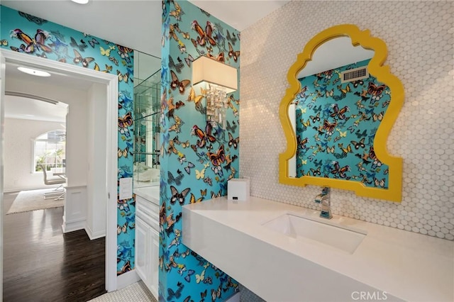 bathroom with wallpapered walls, wood finished floors, vanity, and baseboards