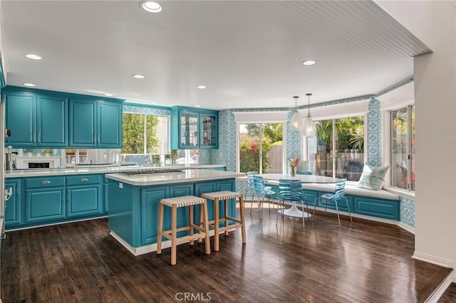 kitchen featuring glass insert cabinets, light countertops, dark wood finished floors, and a center island