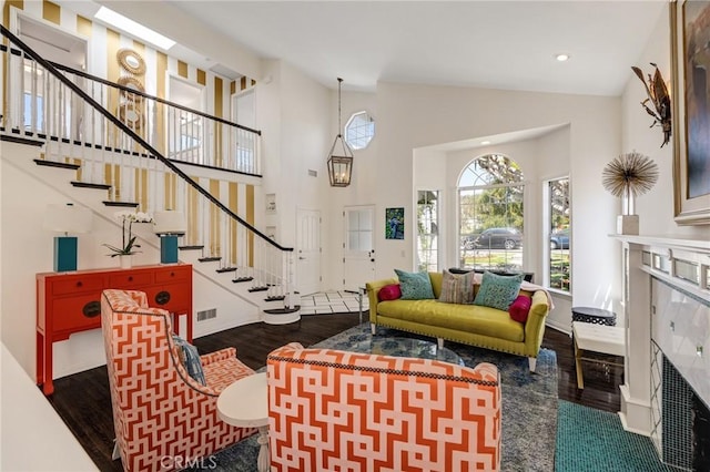 living area featuring visible vents, a fireplace, wood finished floors, high vaulted ceiling, and stairs