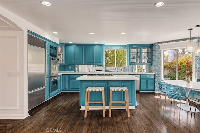 kitchen with light countertops, built in appliances, a kitchen island, and blue cabinetry