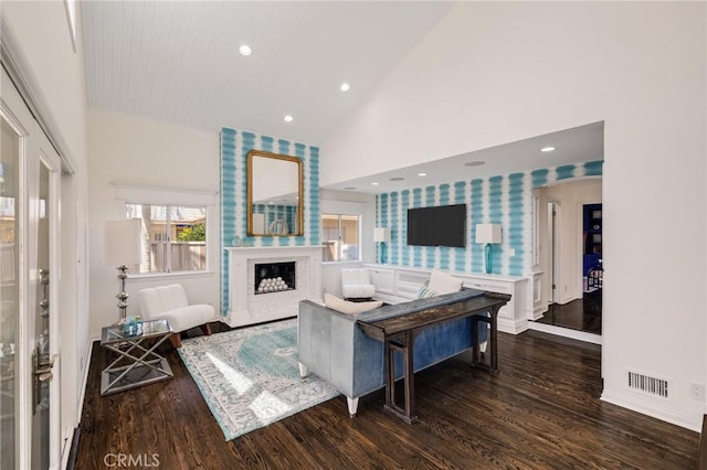 living room with high vaulted ceiling, wallpapered walls, wood finished floors, and a fireplace
