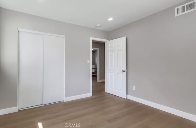 unfurnished bedroom with baseboards, visible vents, wood finished floors, and recessed lighting