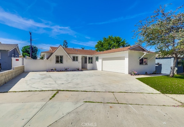 ranch-style house with stucco siding, fence, concrete driveway, and an attached garage