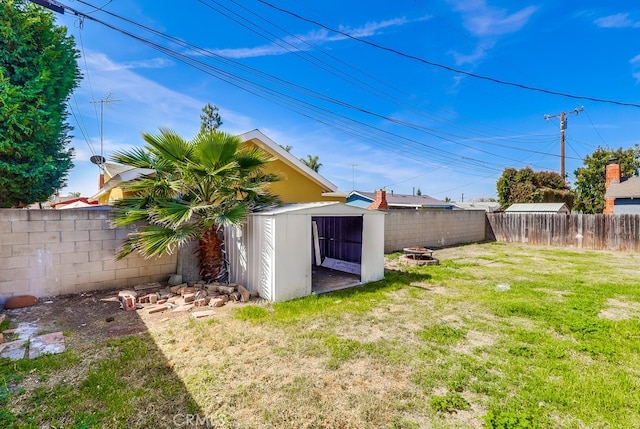 view of yard featuring a storage unit, an outdoor structure, and a fenced backyard